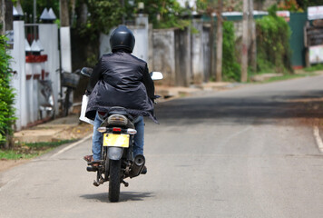 Naklejka premium A man is riding a motorcycle down a street