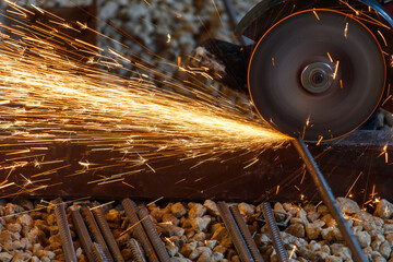 A piece of machinery is cutting through a metal object, creating sparks