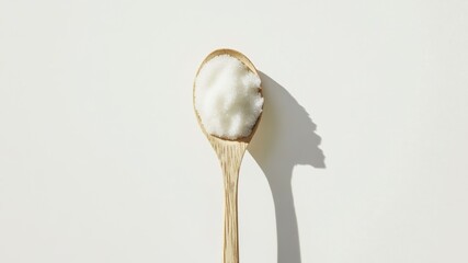 A spoonful of sugar on a white background with a strong shadow.