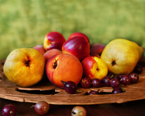 Beautiful summer background of ripe fruits and gooseberries close-up on wooden carved tray