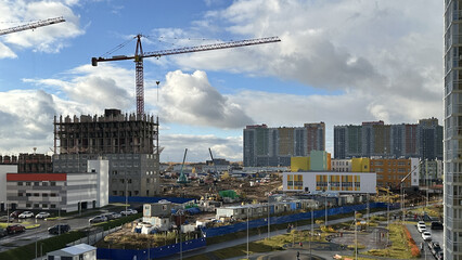 Obraz premium Construction of new multi-storey residential buildings outside the city in Russia. Tower crane operation. Housing construction concept 