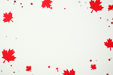 Canada Day frame flat lay. Scattered red paper maple leaves and star confetti border on white background. Festive holiday concept with copy space.