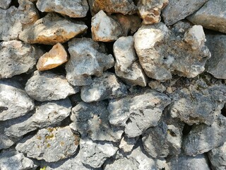 Close-up of a rough stone wall with natural textures and earthy tones. Ideal for backgrounds, construction themes, nature textures, or rustic design elements