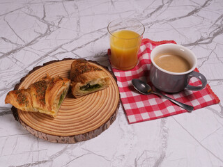 Colazione con brioche al pistacchio, tazza di caffè e bicchiere di succo d'arancia