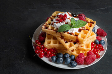 Waffles with fruits on dark background