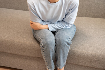Girl in pajamas holding her stomach. Menstruation. Abdominal pain, hands of a woman with abdominal...
