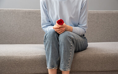 A girl in blue pajamas holds her stomach. There is a red rose next to her as a symbol of...