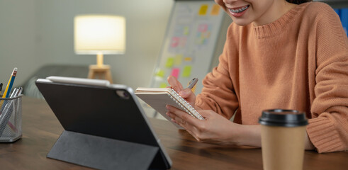 Student studies online on laptop and writing on notebook.