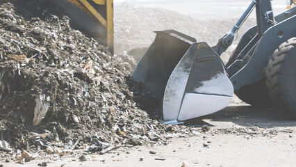 A bulldozer blade collecting waste at a recycling site, representing waste management, environmental sustainability, and industrial recycling processes for a cleaner future.