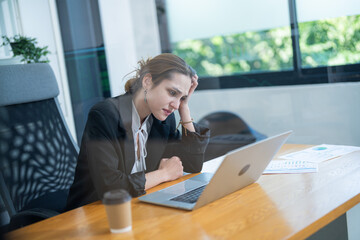 Professional woman working intensely at a laptop in a modern office setting during the afternoon