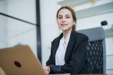 Professional young woman working on a laptop in a modern office setting