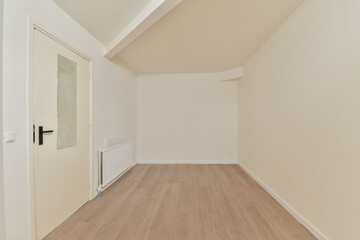 A minimalist interior space featuring plain white walls and wooden flooring, creating a serene atmosphere that emphasizes simplicity and cleanliness.