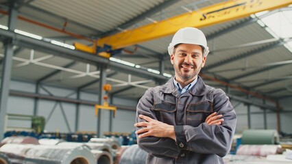 Happy Caucasian worker wearing grey uniform and white helmet at workplace. Enjoying fabrication of...