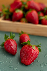 Freshly washed strawberries on a green background with water drops on a blurred background of berries. Seasonal berries. Vitamins.