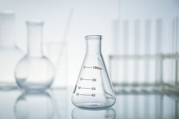 Empty flask on mirror surface against light background. Laboratory equipment