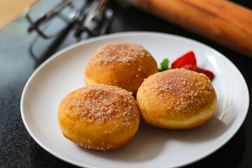A handmade bombolone or bomboloni is an Italian-filled doughnut that is eaten as a snack or dessert. Selective focus.