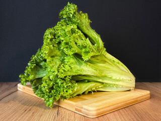Leaf lettuce or better known as selada keriting is a type of lettuce whose leaf tips are wavy and light green in color. On a wooden board and black background