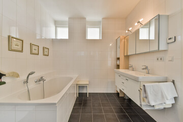 A sleek and contemporary bathroom featuring a bathtub, dual sinks, and stylish mirrors with natural light filtering through the windows, creating a serene ambiance.