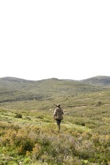 A man is walking in a field with a gun