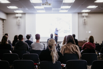 Speaker giving a talk in conference hall at business event. Rear view of unrecognizable people in...