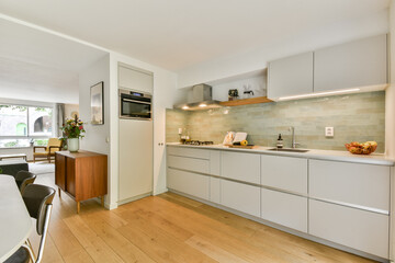 A stylish modern kitchen featuring sleek cabinetry, minimalist decor, and natural light streaming in. The open layout enhances the space's functionality and aesthetic appeal.