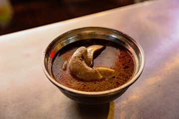 Bowl of Taiwanese pork kidney soup in sesame oil broth, featuring rich red-brown soup with visible kidney slices in a night market setting
