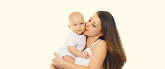 Portrait of happy mother kissing holding baby, young mom and little child on white studio background