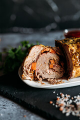 A beautifully presented beef roulade with vibrant vegetable stuffing, served with rich tomato sauce on a dark slate platter. Perfect for gourmet food photography and culinary content. 