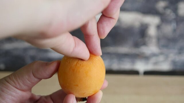 オレンジ色の完熟びわの皮を剥く動画。