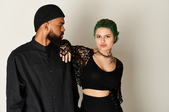 Stylish multicultural couple showcasing trendy outfits and sunglasses in studio setting