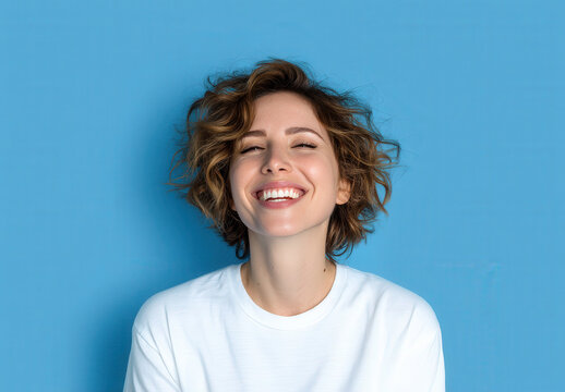 mujer de 30 a&ntilde;os sonriendo, cabello media melena casta&ntilde;o rizado, camiseta blanca, sobre fondo azul cielo con espacio vacio publicitario