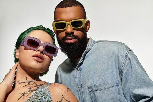 Stylish multicultural couple showcases trendy sunglasses in a vibrant studio setting