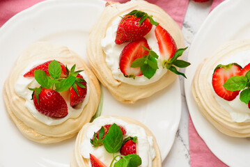 Meringue nests mini pavlovas with whipped cream and strawberries on a plate.top veiw