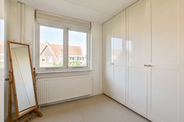 A bright and airy minimalist interior featuring a large mirror, built-in wardrobe, and ample natural light from the window. The overall design is sleek and contemporary.