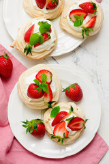 Meringue nests mini pavlovas with whipped cream and strawberries on a plate.top veiw