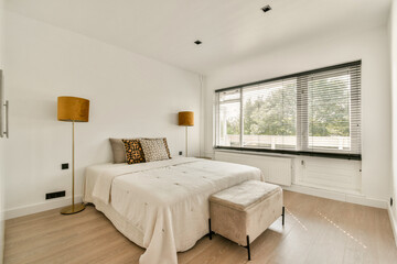 A sleek, minimalist bedroom featuring contemporary furniture, warm lighting, and large windows allowing natural light to fill the space.