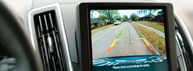 Panorama view suburban residential street with sidewalk in backup camera view on navigation dashboard center console LCD touchscreen, modern technology smart sensors detect, assist parking, Texas
