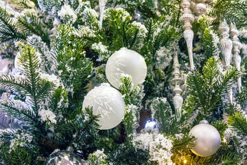 Beautifully decorated Christmas tree with delicate white ornaments, white baubles and frosted icicles. 