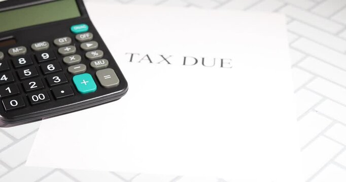 The image features a standard calculator placed atop a white sheet of paper with the bold text &ldquo;TAX DUE.&rdquo;