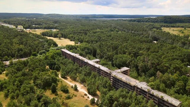 Aerial drone view of decaying Prora buildings lost in dense forest on R&uuml;gen Island, evoking eerie silence and forgotten history.