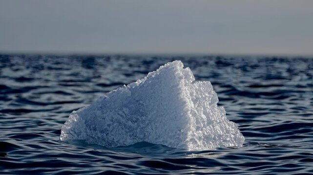 Iceberg in the arctic. A splinter of ice on the sea waves. A glare of light in the shadow of nature. Glacier in the arctic lifestyle.