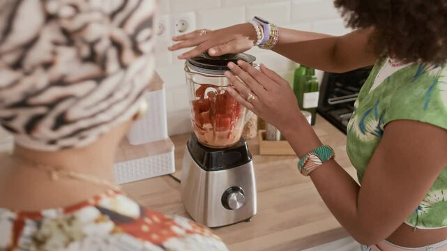 View from above of multi-ethnic daughter and mom using blender when cooking together at home kitchen