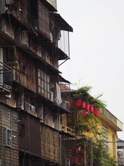 
Urban street scene in Hanoi, Vietnam, with old apartment buildings, air conditioners, and traditional red lanterns hanging above narrow balconies.