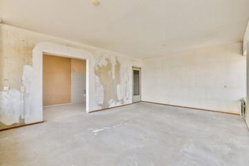 Fototapeta premium A bare interior space showcasing unfinished walls with peeling paint and a clean floor. The room appears ready for renovation or redesign.
