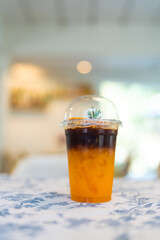 iced coffee blended with orange juice, decorated with rosemary, show two tone layers, fusion drink....