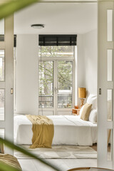 A serene bedroom featuring a comfortable bed, ample natural light streaming through large windows, and a calming decor that promotes relaxation.