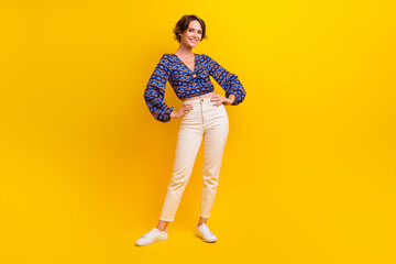 Fototapeta premium Full body length photo of candid girl posing model in retro summer shirt touching waist and white pants isolated on yellow color background