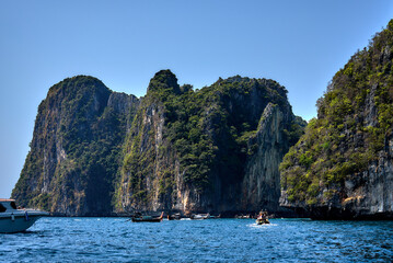 Impressive stone cliffs meet the vibrant turquoise waters of the thai sea
