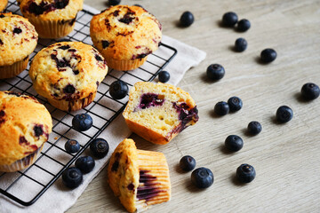 Close-up of vanilla muffins with blueberries on metal mesh tray and cotton towel near blueberries...