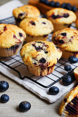 Close-up of vanilla muffins with blueberries on metal mesh tray and cotton towel near blueberries...